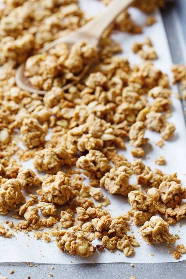 Granola on parchment paper and on a wooden spoon.