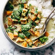 Utensils sit in a bowl of rice, vegetables and tofu.
