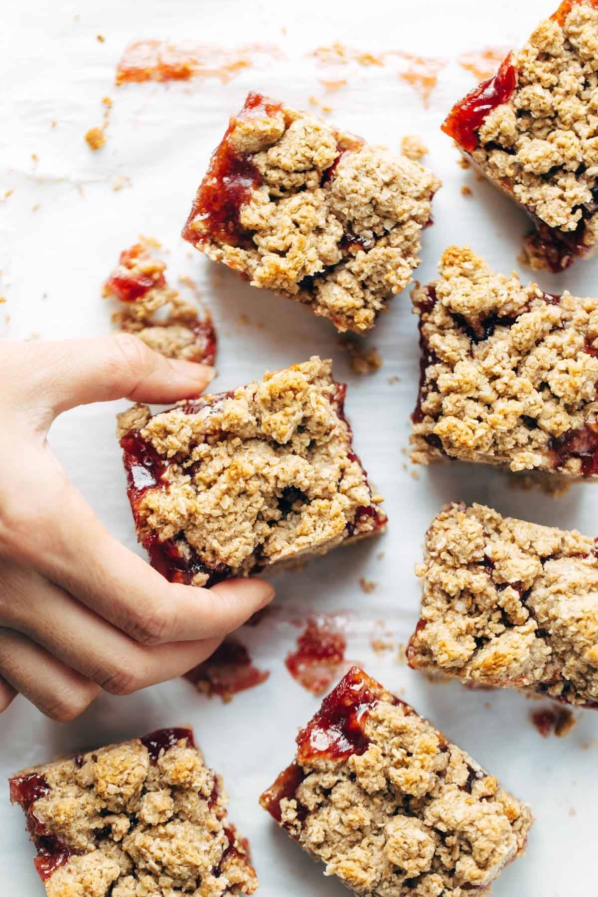 Hand grabbing Strawberry Oat Crumble Bars 