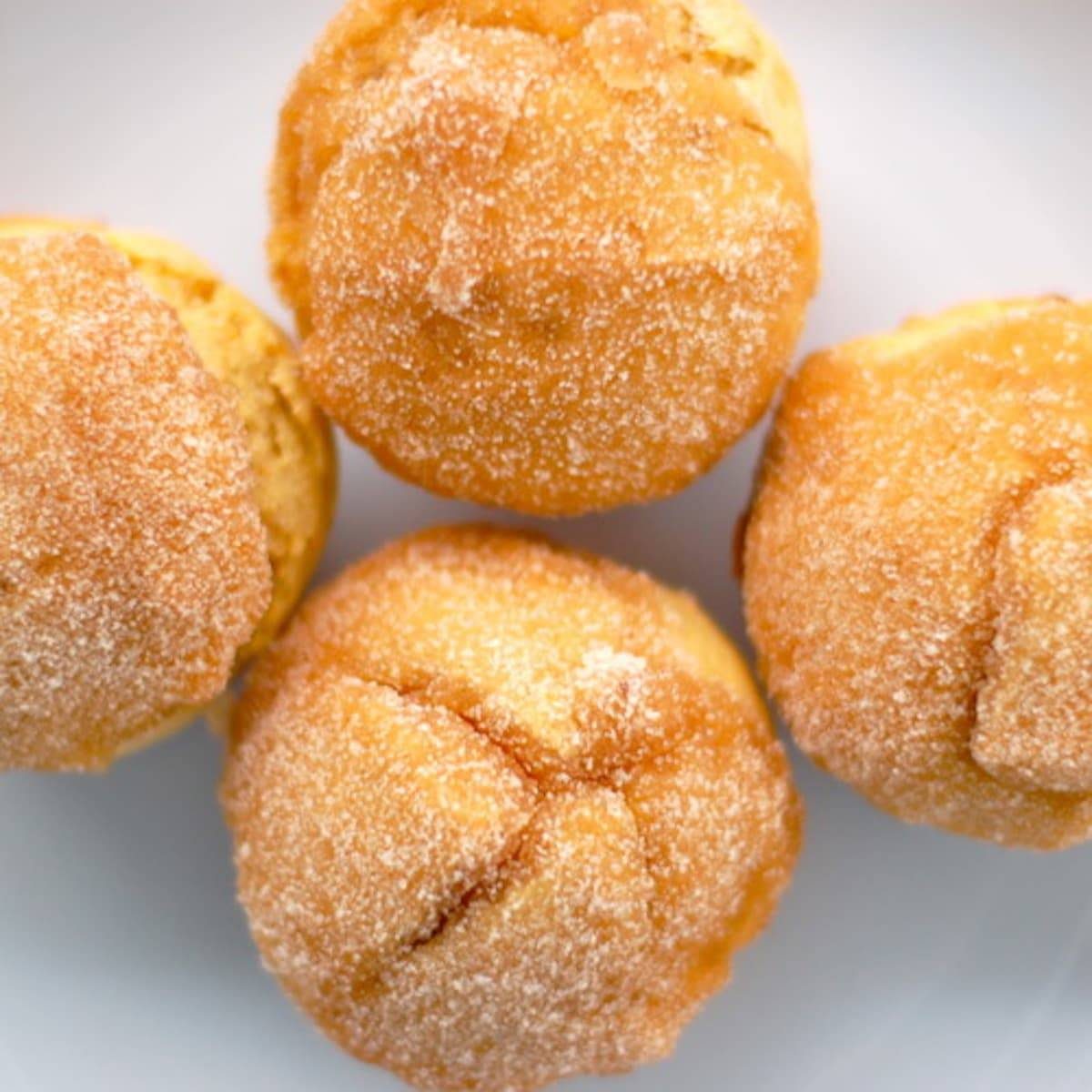 Four sugar-dusted sweet potato muffins.