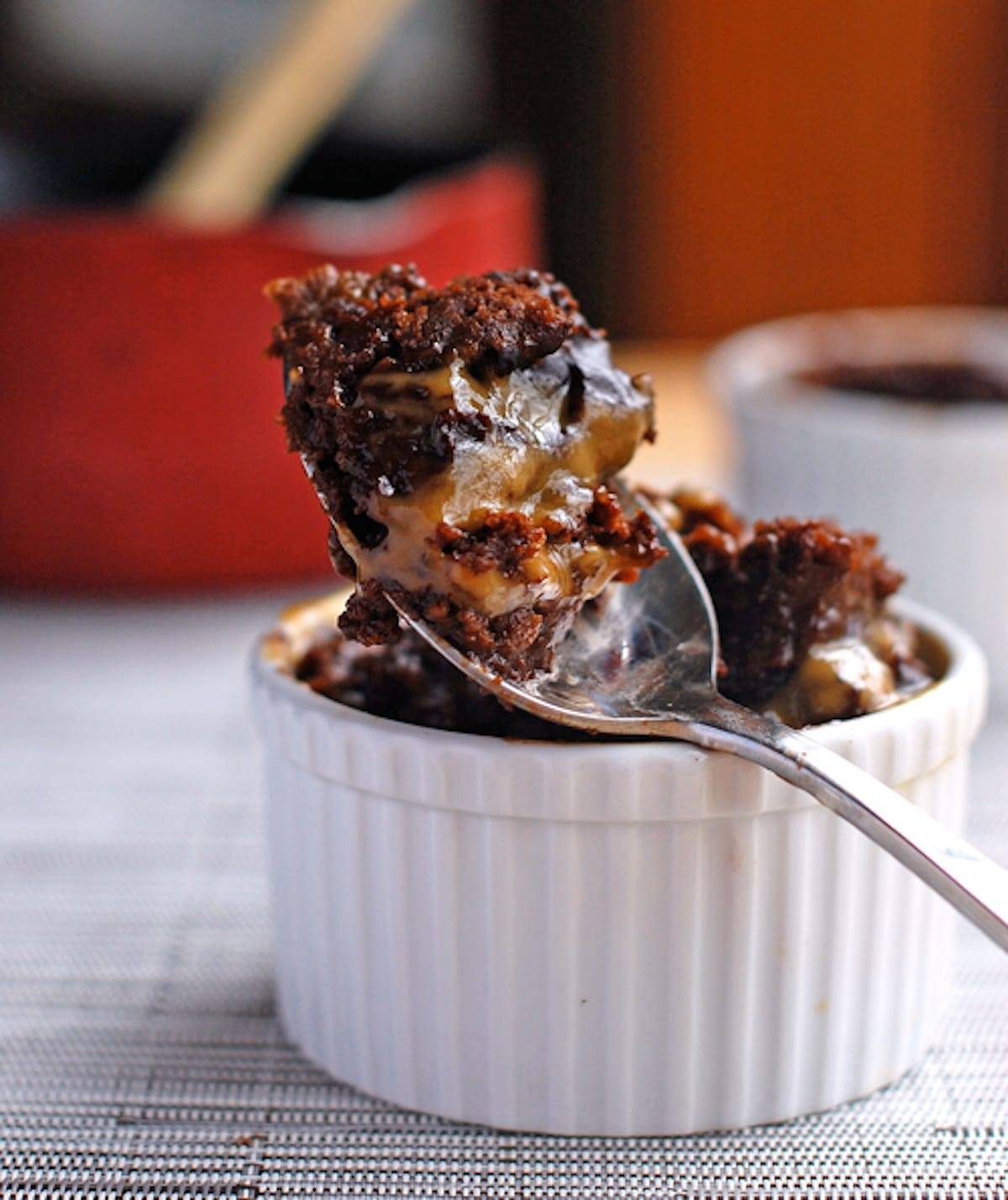 Hot fudge cake covered with homemade peanut butter sauce on a spoon on a white dish.